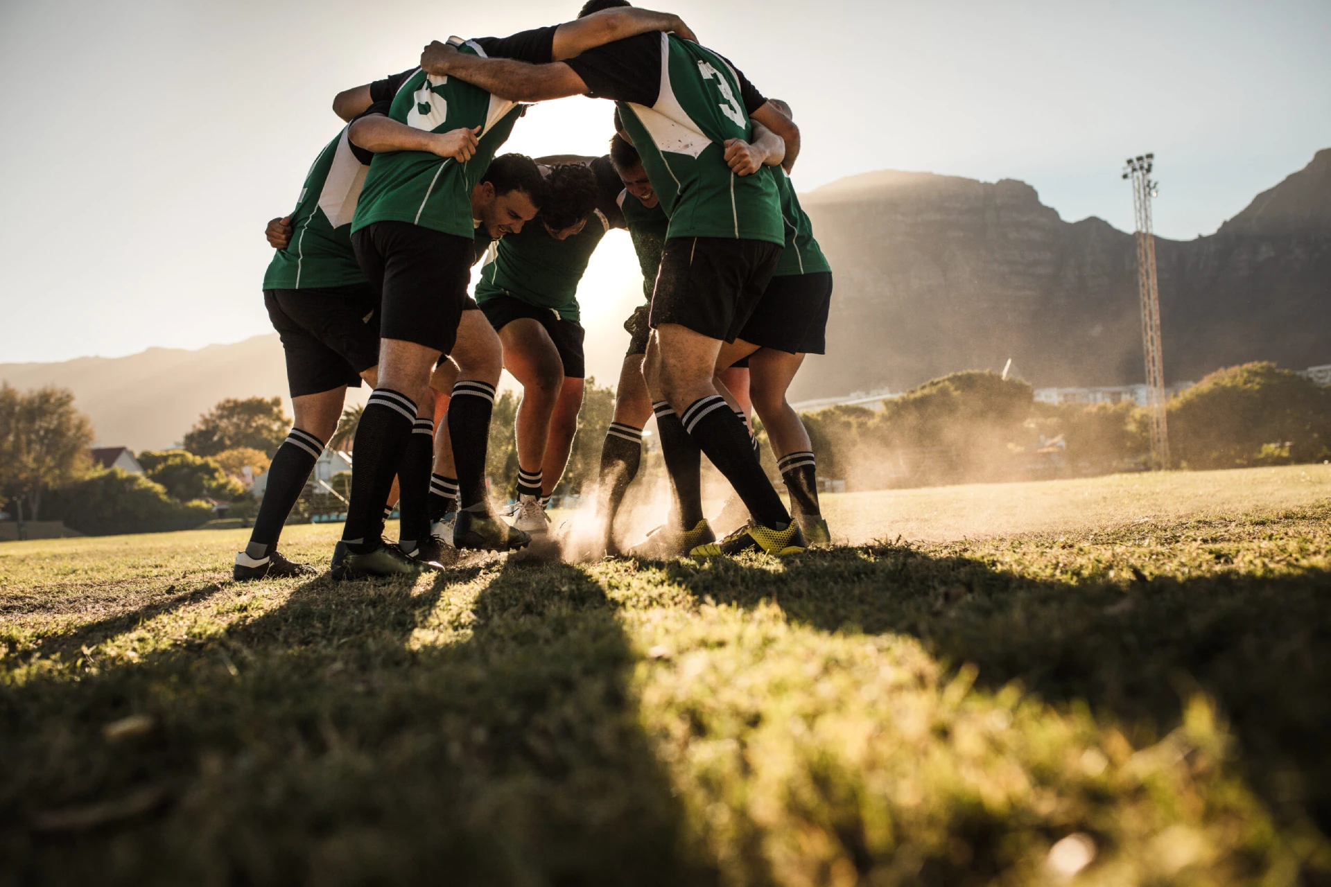 Rugby,Players,In,A,Huddle,Rubbing,Their,Feet,On,Grass.